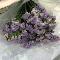 a bunch of purple flowers sitting on top of a white cloth covered table next to a skateboard