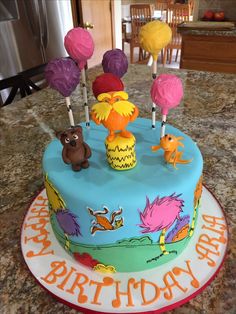 there is a birthday cake decorated with lollipops and animals on the table