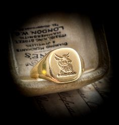 This Antique ring has a striking sleek design with a carved intaglio of a heraldic bull set against a crisp yellow gold background A solid and weighty ring at 6.4 grams, you can feel the craftsmanship that went into the making of this ring The crisp intaglio depicts a a powerful image of a bull, with its two upright ears and horns and highly textured body. A bull in a coat of arms  represents valour and magnanimity, bravery and generosity. The horns represent strength and fortitude It holds lovely crisp hallmarks Historically, intaglios were intended for use as portable wax seals, Prominent individuals in the Roman Empire had their own unique intaglios, often carved in carnelian, to be used as wax seals for important documents The origin of intaglios can be traced back to 5000BC, proving t Classic Yellow Gold Signet Ring With Maker's Mark, Symbolic Formal Signet Ring Hallmarked, Symbolic Hallmarked Signet Ring For Formal Occasions, Formal Symbolic Hallmarked Signet Ring, Luxury Carved Yellow Gold Signet Ring, Classic Ceremonial Engraved Intaglio Ring, Classic Yellow Gold Signet Ring With Intaglio, Classic Ceremonial Signet Ring With Intaglio, Ceremonial Classic Intaglio Rings