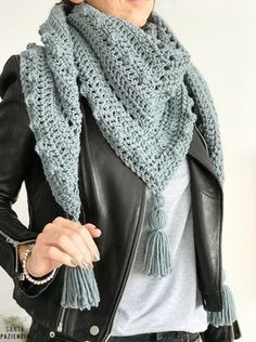 a woman wearing a black leather jacket and a blue knitted scarf with tassels