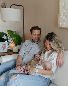 a man and woman sitting on a couch holding a baby