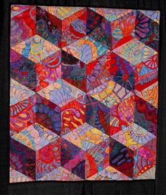 a colorful quilt is displayed on a black background with an orange and red design in the center