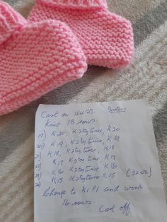 a pink knitted mitt next to a handwritten note on a bed sheet