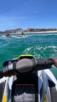 a person riding on the back of a boat in the ocean with other people behind them