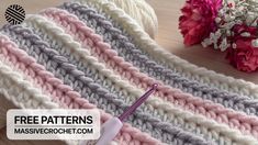 a crocheted blanket with yarn and knitting needles next to it