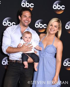 a man and woman holding a baby in front of a black background with an abc logo