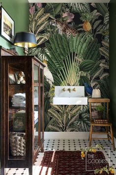 the bathroom is decorated with tropical wallpaper and green walls, along with a white sink