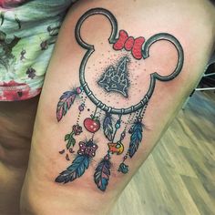 a woman's leg with a mickey mouse tattoo on it and dream catchers