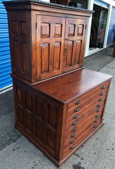 two large wooden drawers sitting next to each other on top of a sidewalk in front of a building