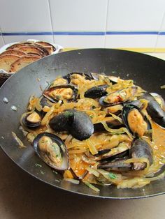 a pan filled with clams and pasta on top of a table