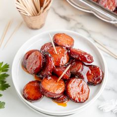 a white plate topped with cooked sausages and skewered toothpicks on top of it