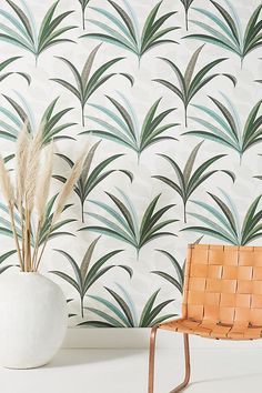 an orange chair sitting in front of a wallpapered with palm leaves and grass