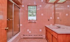 a bathroom with pink tiled walls and flooring next to a bathtub, sink, and shower