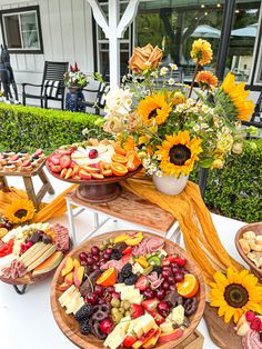 a table topped with lots of different types of food on wooden trays next to flowers