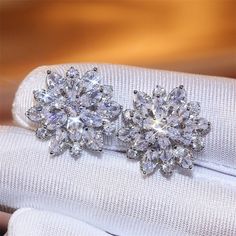 two diamond earrings sitting on top of a white glove