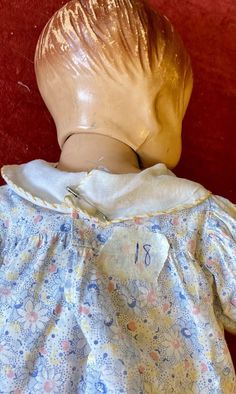 an infant doll wearing a blue dress with flowers on it's chest and head