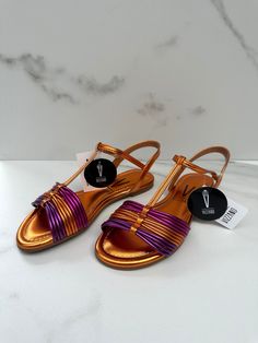 These bright orange flat sandals with orange and purple straps are perfect for adding a pop of color to your outfit. The ankle strap ensures a secure and comfortable fit, while the vibrant colors of the straps add a playful touch. These sandals are versatile and can be worn on a casual day out or dressed up for a summer party. The flat sole provides all-day comfort, making them the perfect addition to your summer shoe collection. Get ready to turn heads with these eye-catching sandals! Adjustable Ankle Strap Sandals In Orange, Adjustable Ankle Strap Orange Sandals, Purple Adjustable Sandals For Party, Purple Flat Sandals For Party, Purple Ankle Strap Sandals For The Beach, Waterproof Slippers, Orange Flats, Metallic Orange, Pattern Flip Flops