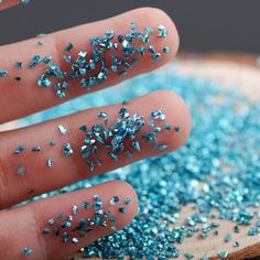 a person's hand with blue glitter sprinkles on their thumb and fingers