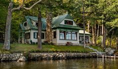 a house sitting on top of a lake surrounded by trees