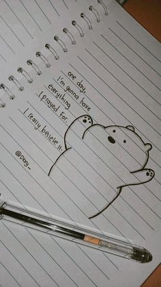 a notepad with writing on it and a pen sitting next to it, in front of a drawing of a bear