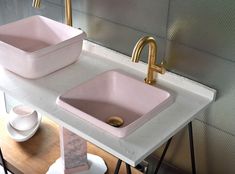 two pink sinks sitting next to each other on top of a white marble countertop