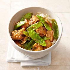 a white bowl filled with chicken and green beans on top of rice covered in sauce