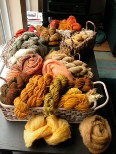 several skeins of yarn sitting on a table next to a basket with balls of yarn