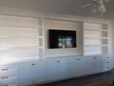 a flat screen tv mounted to the side of a white entertainment center in a living room