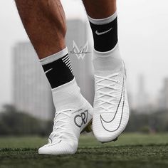 the legs and feet of a man in white shoes with black socks standing on grass