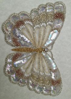 a white and gold brooch sitting on top of a table next to a wall