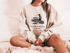 A uniquely designed Polar Express sweatshirt. All rights for characters and book references to Chris Van Allsburg.  -The collar is ribbed knit, so it retains its shape even after washing. There are no itchy side seams on these sweaters! -50% cotton, 50% polyester -Loose fit -Runs true to size Winter Crew Neck T-shirt For Loungewear, Chris Van Allsburg, Michigan Sweatshirt, The Polar Express, Polar Express, Sweatshirt Christmas, Bookish Gifts, Gifts For Readers, Unique Christmas