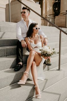 a man and woman sitting on the steps together, one holding a bouquet in her hand