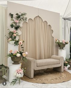 a living room filled with furniture and flowers on the floor next to a wall covered in drapes