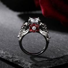 a close up view of a ring with red and white stones in it on a black surface