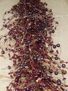 some red berries and brown leaves on a tableclothed surface, with the stems sprouting from them