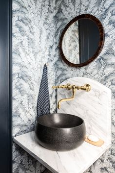 a bathroom sink sitting under a mirror next to a black bowl on top of a counter