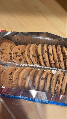 an assortment of cookies and chocolate chip cookies in a package on a table next to a cup of coffee