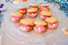 some cookies with pink frosting and white sprinkles on a clear plate