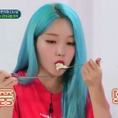 a woman with blue hair eating food from a spoon