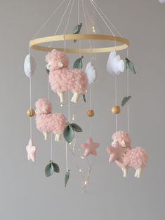 a pink sheep mobile hanging from a circular wooden chandelier with stars and leaves