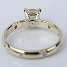 a yellow gold engagement ring with a princess cut diamond in the center and small diamonds on the side