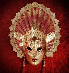 Crafted in sultry red and gold, this decadent mask's most alluring feature is its extended fan-shaped headpiece. Composed of applique, hand-bent metal, and crystals, this mask will lend its wearer an air of regal seductiveness that won't be easily forgotten by those who behold it. Handmade in Italy and is accompanied b Luxury Artistic Masks For Carnival, Luxury Artistic Red Masks And Prosthetics, Full Face Red Mask For Masquerade, Red Full Face Mask For Masquerade, Red Full Face Carnival Mask, Red Venetian Mask For Masquerade, Red Venetian Masquerade Mask, Red Full Face Mask For Carnival, Elegant Gold Masquerade Mask For Theater