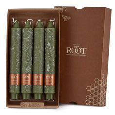 four green candles in a cardboard box next to a card board with the word root on it