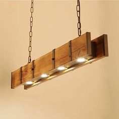 a wooden light fixture with three lights on the bottom and two chains hanging from it