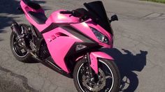 a pink motorcycle is parked on the street