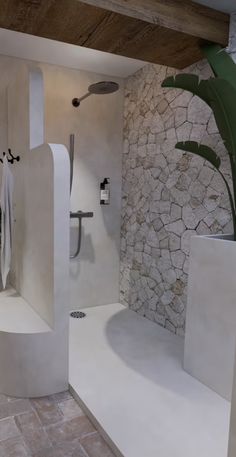 a modern bathroom with stone walls and flooring, including a large plant in the corner