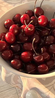 a white bowl filled with cherries on top of a table