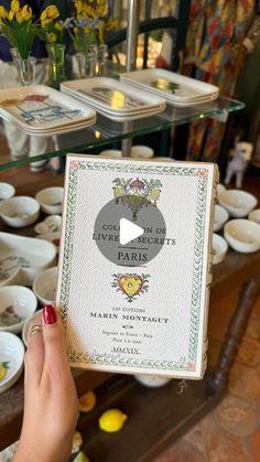 a person holding up a book in front of plates