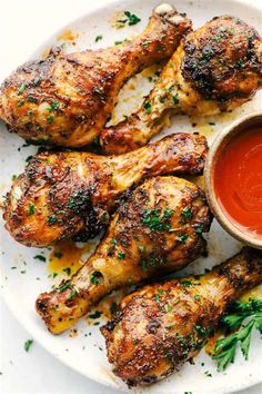 grilled chicken wings on a plate with dipping sauce and parsley sprigs