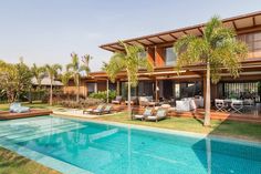 an outdoor swimming pool with lounge chairs and palm trees surrounding the pool is surrounded by lush greenery